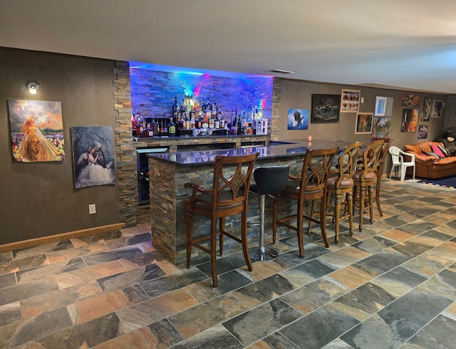 bar featuring a dry bar, stone finish flooring, wine cooler, and visible vents