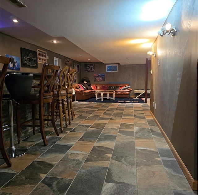 interior space featuring baseboards, stone finish flooring, visible vents, and recessed lighting