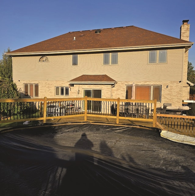 back of property featuring a chimney and a wooden deck