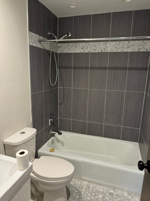 bathroom featuring tile patterned flooring, tiled shower / bath combo, and toilet