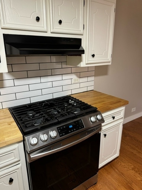 kitchen featuring light hardwood / wood-style floors, tasteful backsplash, gas stove, white cabinets, and butcher block countertops