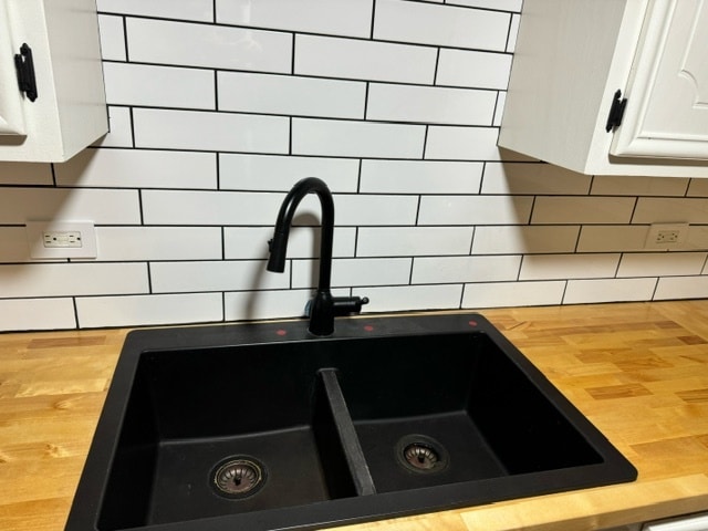 details with wood counters, white cabinetry, sink, and backsplash