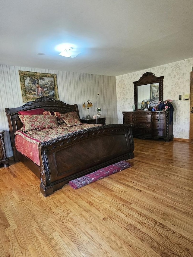 bedroom featuring wood finished floors and wallpapered walls