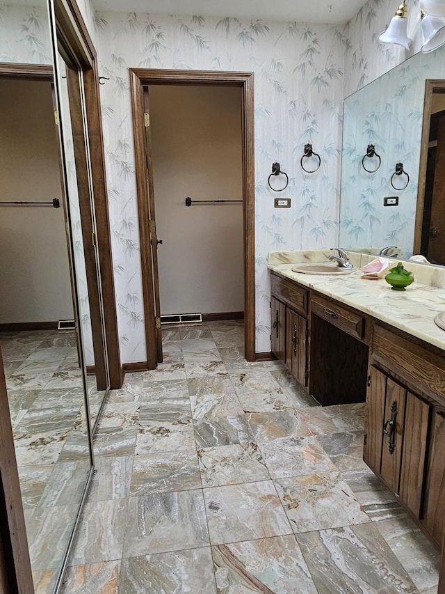 full bath featuring visible vents, vanity, baseboards, and wallpapered walls