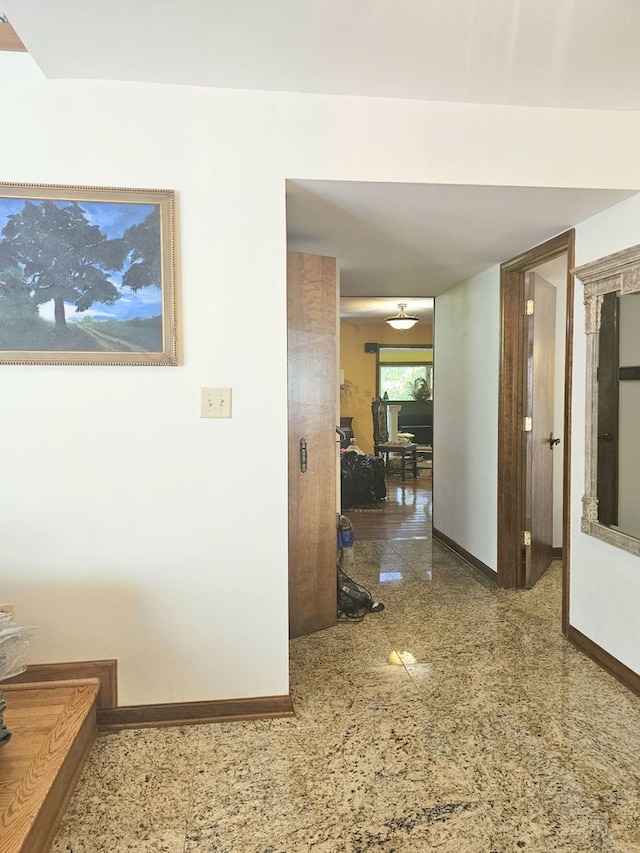 hallway featuring granite finish floor and baseboards