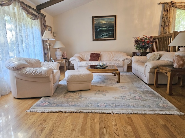 living area with lofted ceiling with beams and wood finished floors