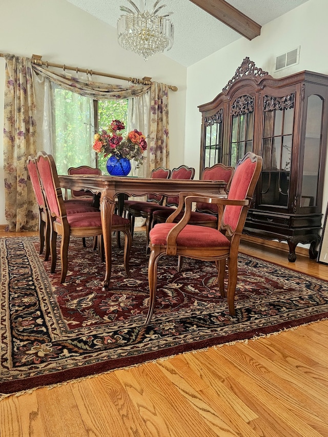 dining area with an inviting chandelier, visible vents, a textured ceiling, and wood finished floors