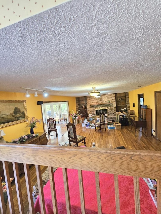 living room with rail lighting, a fireplace, a textured ceiling, and wood finished floors