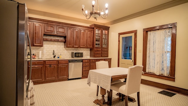 kitchen with stainless steel appliances, sink, ornamental molding, an inviting chandelier, and hanging light fixtures