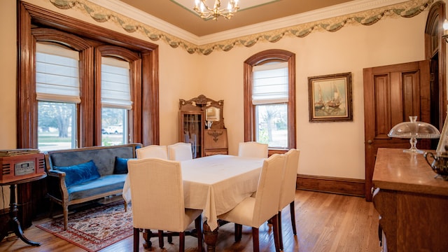 dining area with ornamental molding, hardwood / wood-style floors, and an inviting chandelier