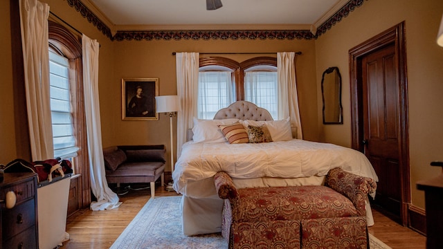 bedroom with light hardwood / wood-style floors, multiple windows, and ornamental molding