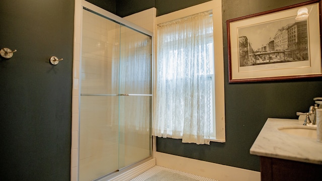 bathroom with a shower with shower door, vanity, and tile patterned floors