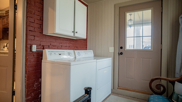 washroom with separate washer and dryer, brick wall, and cabinets