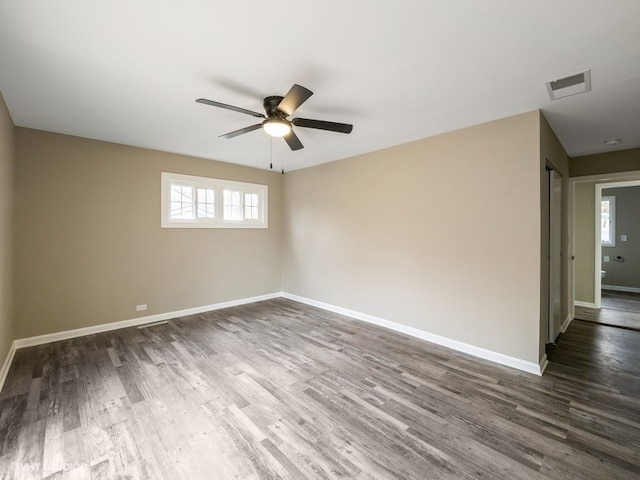 spare room featuring ceiling fan, a healthy amount of sunlight, and dark hardwood / wood-style floors