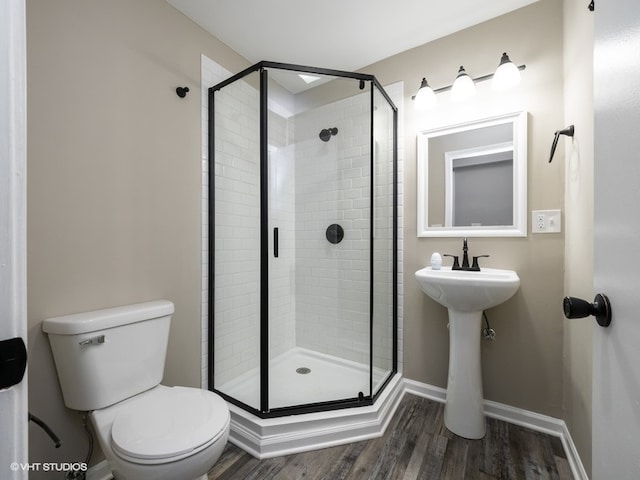 bathroom with wood-type flooring, toilet, and an enclosed shower