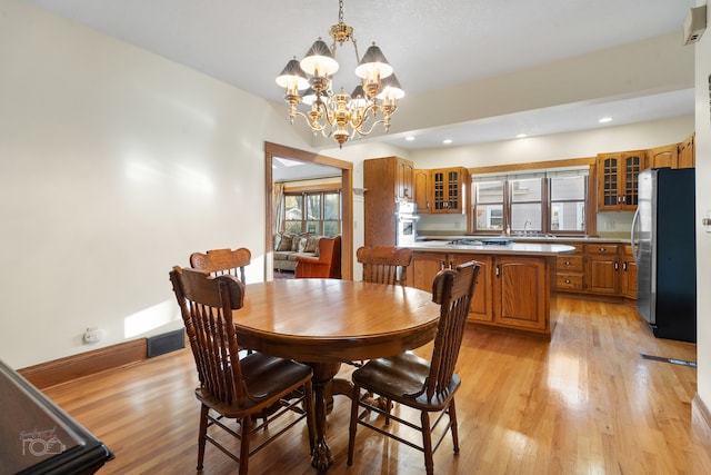 dining area with sink, light hardwood / wood-style flooring, and an inviting chandelier