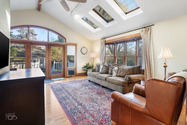 living room with plenty of natural light, light hardwood / wood-style floors, beam ceiling, and ceiling fan