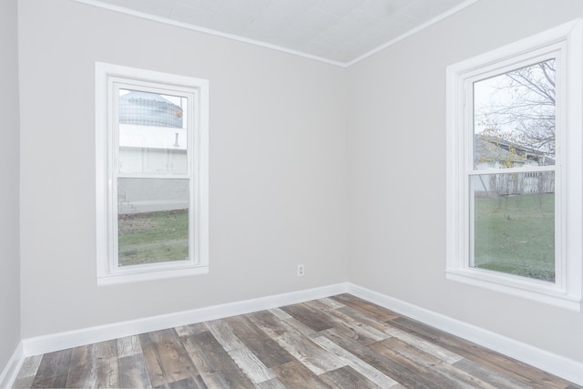 empty room with hardwood / wood-style flooring and crown molding