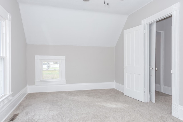 additional living space with ceiling fan, lofted ceiling, and light colored carpet