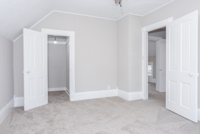 unfurnished bedroom with a closet, lofted ceiling, and light carpet