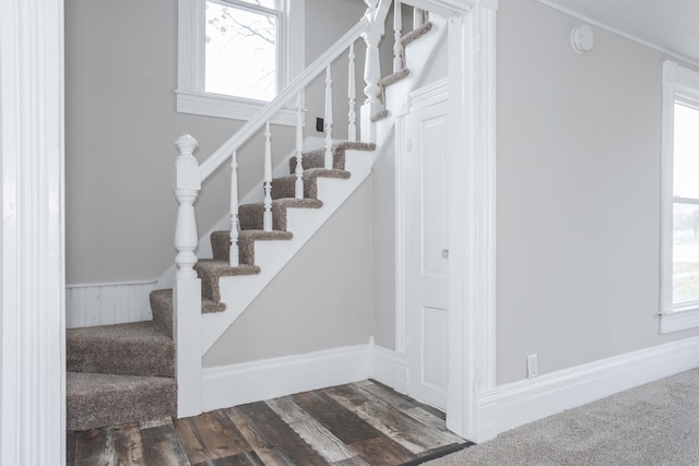 staircase with hardwood / wood-style floors, ornamental molding, and a healthy amount of sunlight