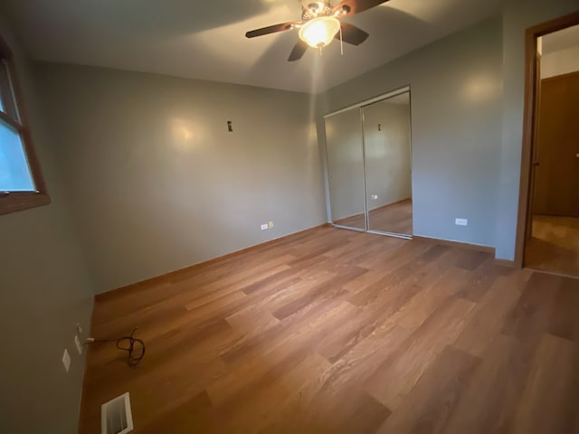 unfurnished bedroom with ceiling fan, a closet, and wood-type flooring