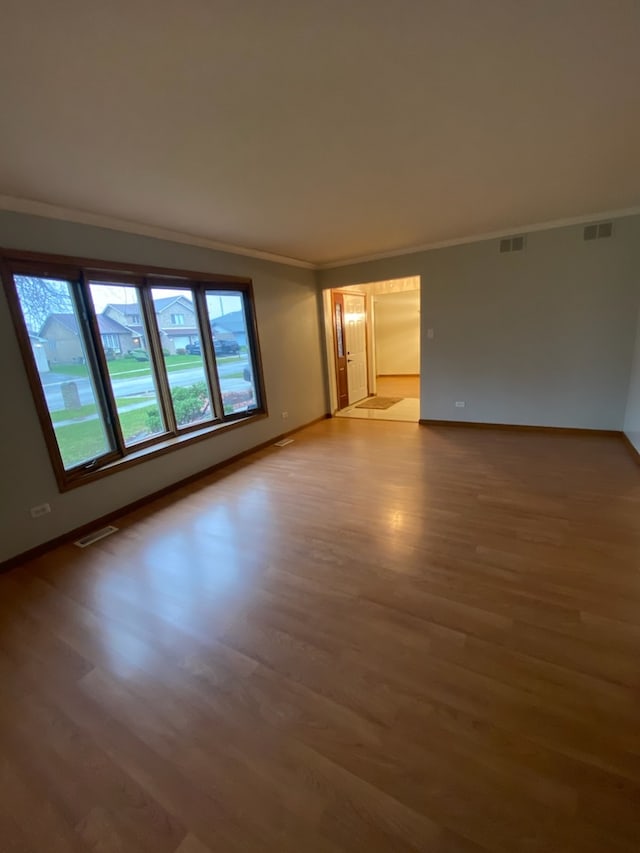 empty room with hardwood / wood-style flooring and crown molding