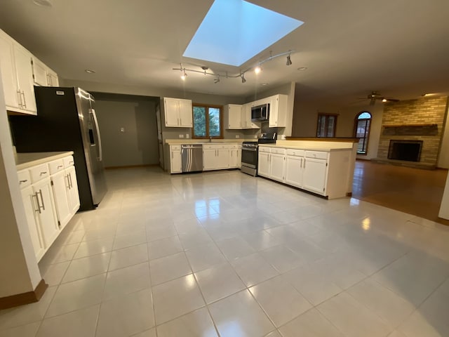 kitchen with kitchen peninsula, appliances with stainless steel finishes, and white cabinetry