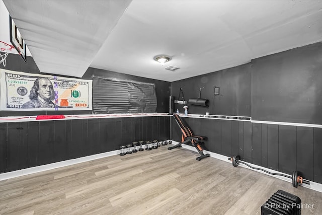 workout room featuring wood walls and light wood-type flooring