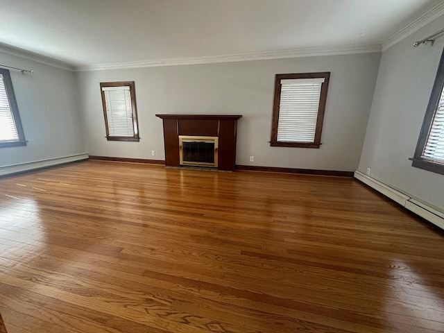 unfurnished living room with hardwood / wood-style floors, a healthy amount of sunlight, baseboard heating, and crown molding