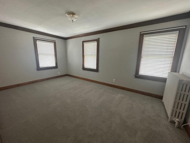 unfurnished room featuring crown molding, radiator heating unit, and carpet