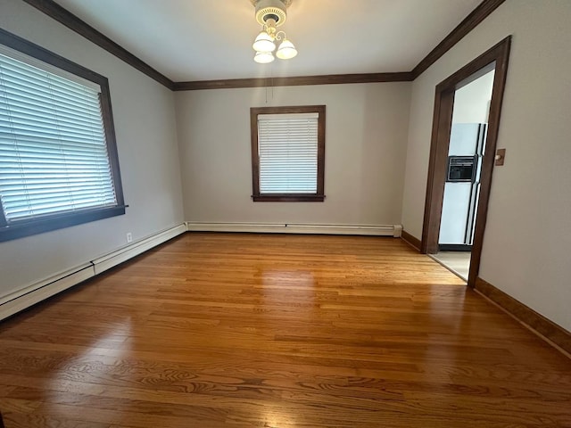 empty room with light hardwood / wood-style floors, crown molding, and a baseboard heating unit