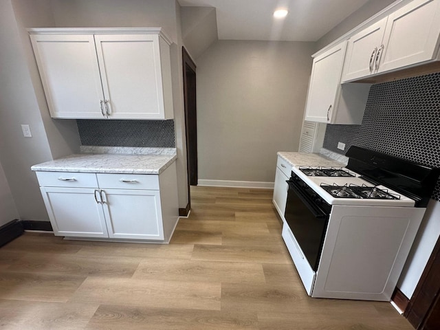 kitchen with light hardwood / wood-style floors, white cabinetry, tasteful backsplash, and white gas stove