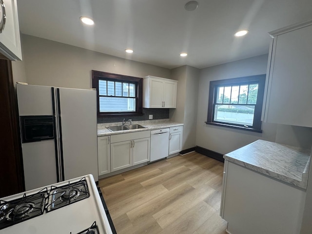 kitchen featuring white appliances, sink, light wood-type flooring, tasteful backsplash, and white cabinetry