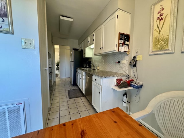 kitchen with sink, tasteful backsplash, light tile patterned floors, stainless steel appliances, and white cabinets