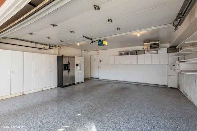 garage featuring stainless steel fridge with ice dispenser and a garage door opener