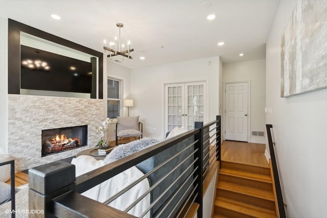 interior space with hardwood / wood-style flooring, a fireplace, french doors, and an inviting chandelier