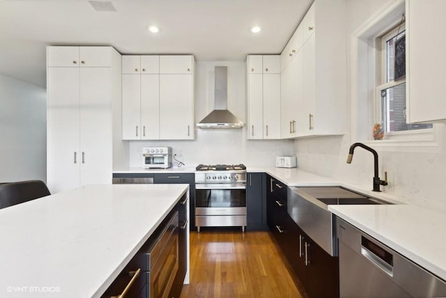 kitchen featuring sink, wall chimney exhaust hood, dark hardwood / wood-style floors, white cabinetry, and stainless steel appliances