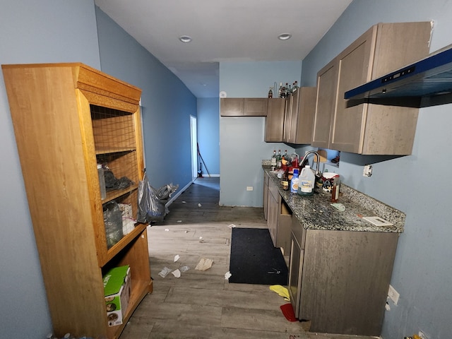 kitchen featuring dark stone counters, extractor fan, and dark hardwood / wood-style floors