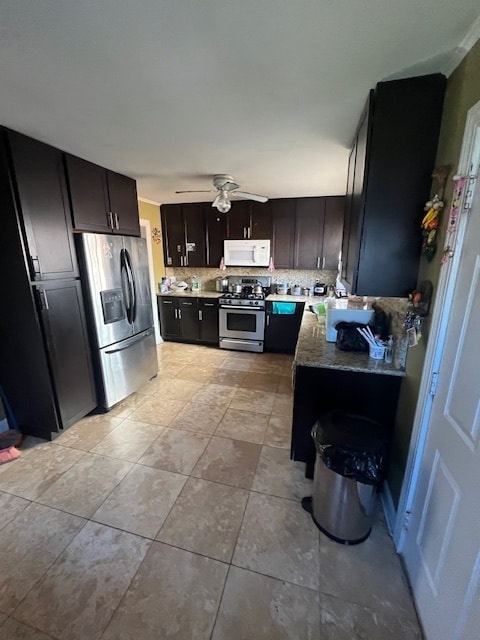 kitchen with dark brown cabinets, decorative backsplash, stainless steel appliances, and light stone countertops