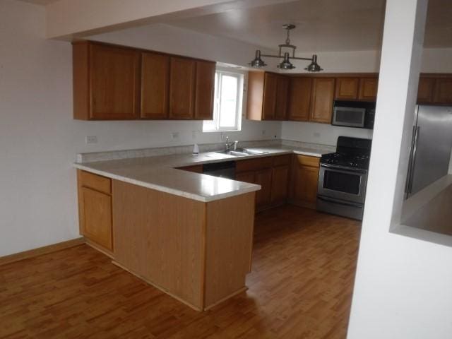 kitchen featuring sink, kitchen peninsula, stainless steel appliances, and light hardwood / wood-style flooring