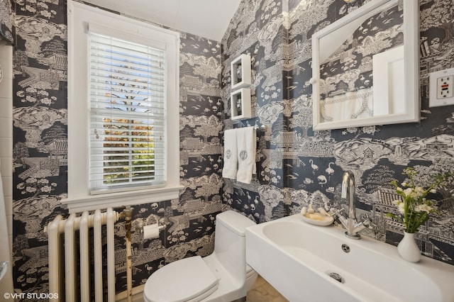 bathroom with radiator, a wealth of natural light, sink, and toilet