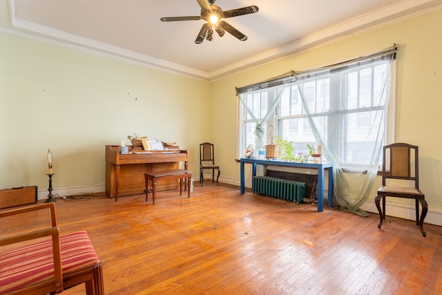 living area featuring radiator, crown molding, hardwood / wood-style floors, and ceiling fan