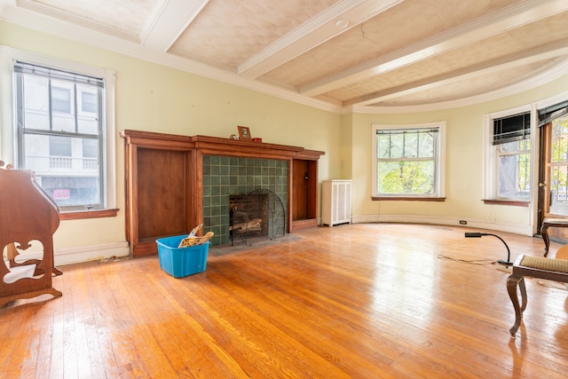 unfurnished living room with beam ceiling, a fireplace, radiator heating unit, and light wood-type flooring