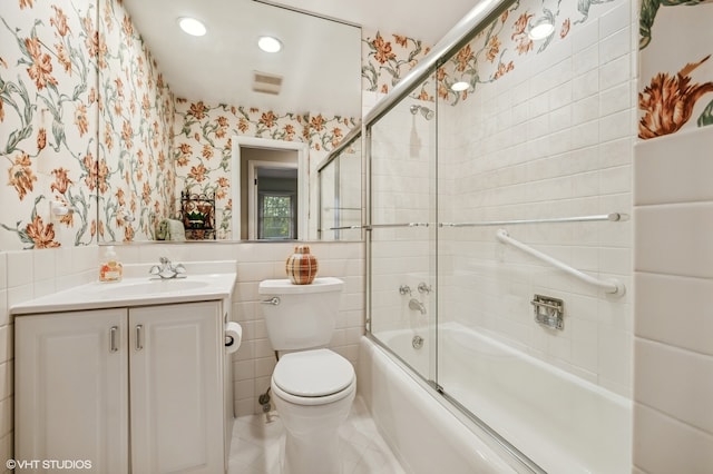 full bathroom featuring shower / bath combination with glass door, vanity, tile walls, and toilet