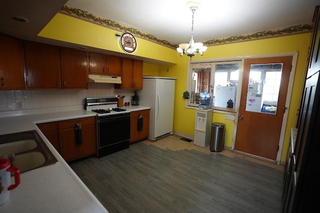 kitchen featuring white appliances, backsplash, sink, hanging light fixtures, and a chandelier