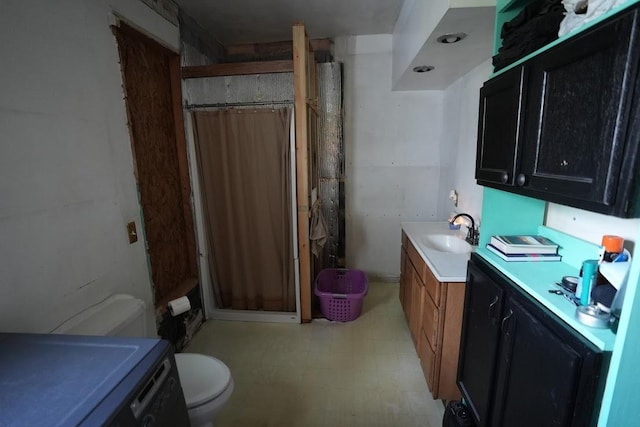 bathroom with vanity, toilet, walk in shower, and washer / dryer