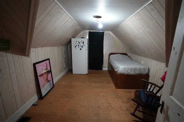 bedroom with wooden walls, vaulted ceiling, and white refrigerator