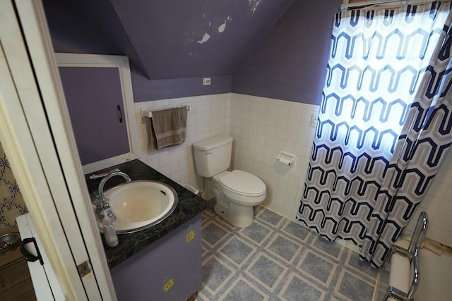 bathroom with vanity, toilet, tile walls, and walk in shower