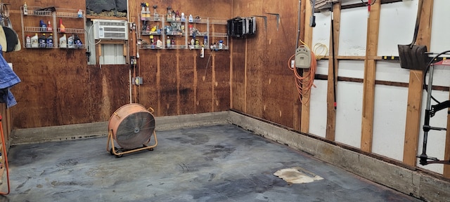 interior space featuring a wall mounted air conditioner, wood walls, and concrete floors